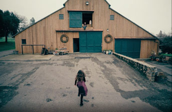 Video still of girl running toward barn